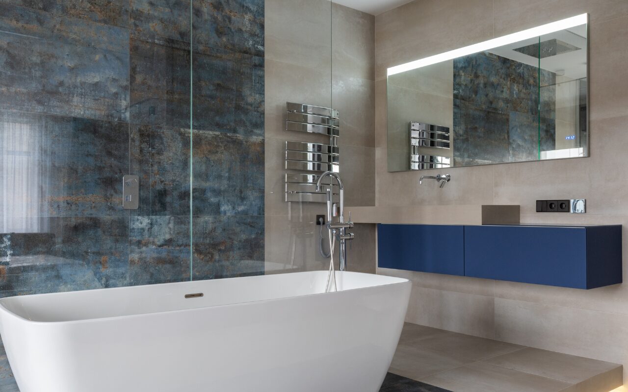 Moderne badeværelse med hvidt badekar og et stort flisebelagt vægdesign med mønster