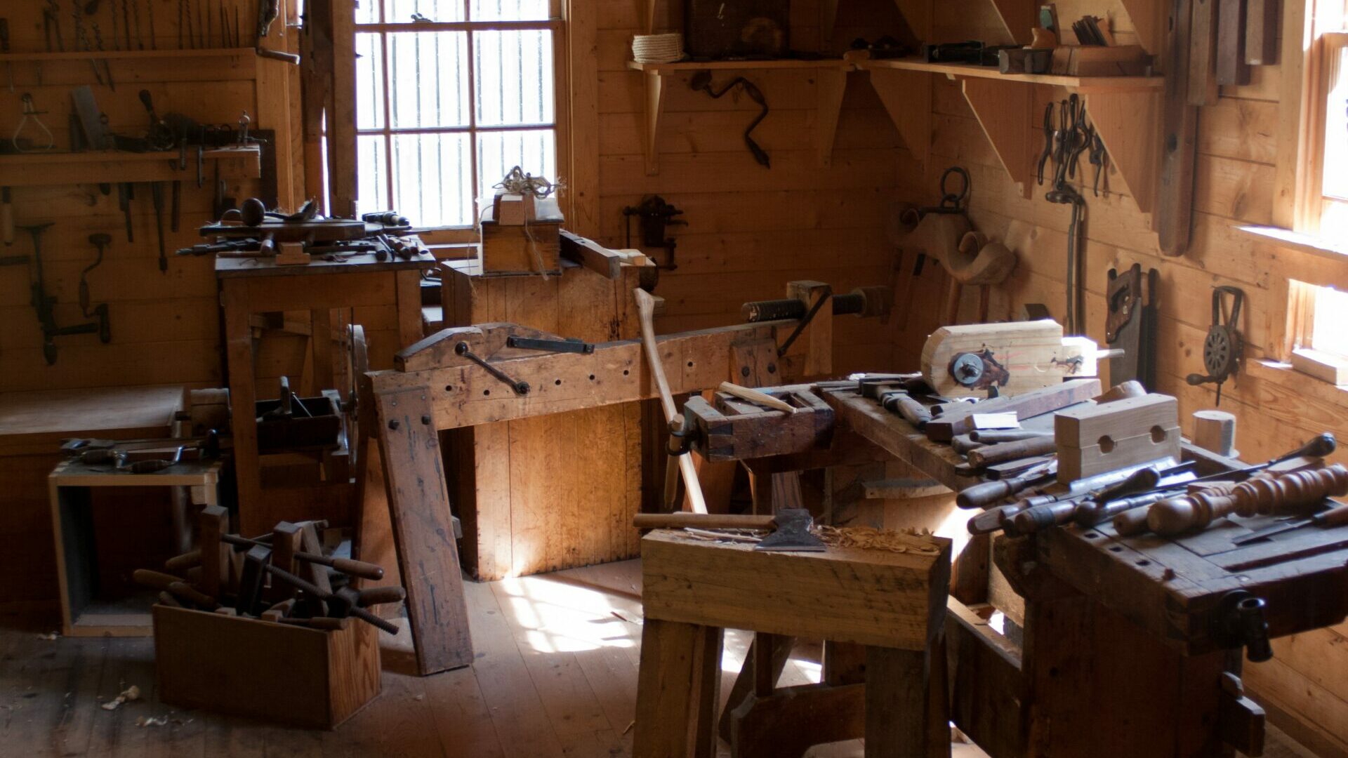 værksted med trævægge og træmøbler og mange forskellige typer værktøj som ligge på møblerne og hænger på væggene