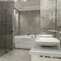 Badeværelse med grå vægge og 2 hvide vaske og et stort hvidt badekar