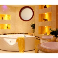 Lyst luksusbadeværelse i helt gule, orange og lyserøde farver. Der er et stort spabad i midten foran store hylde med gul og orange belysning hvor der står dyreornamenter