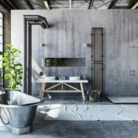 Industrielt badeværelse med grå rustikt badekar på et gråt rustikt gulv foran en grå væg. Der er eksponeret rørføring og træmøbler